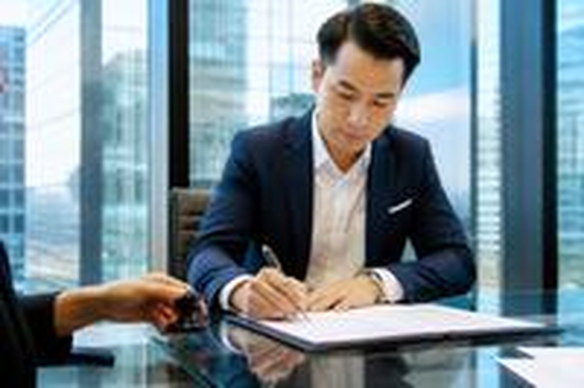 A client signs loan documents at an office table
