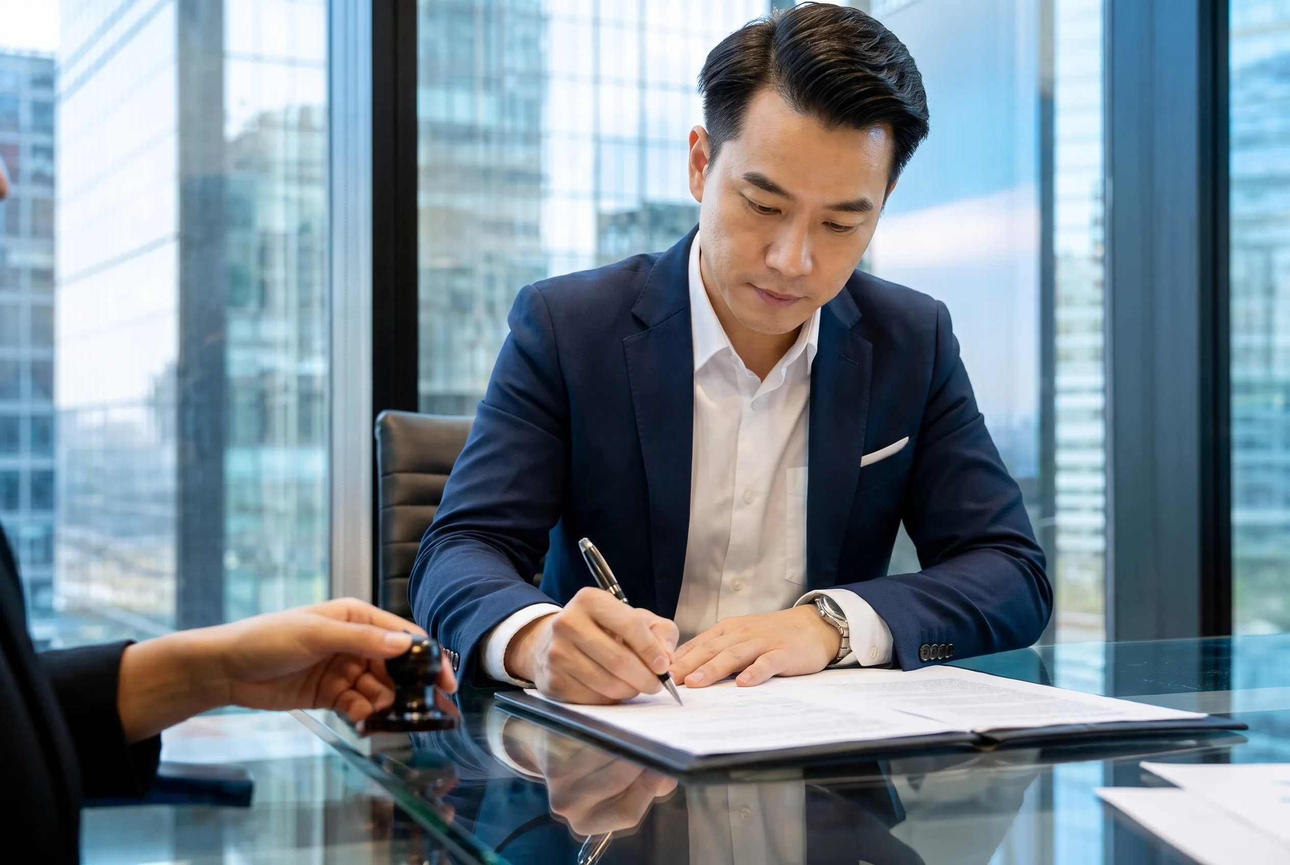A client signs loan documents at an office table