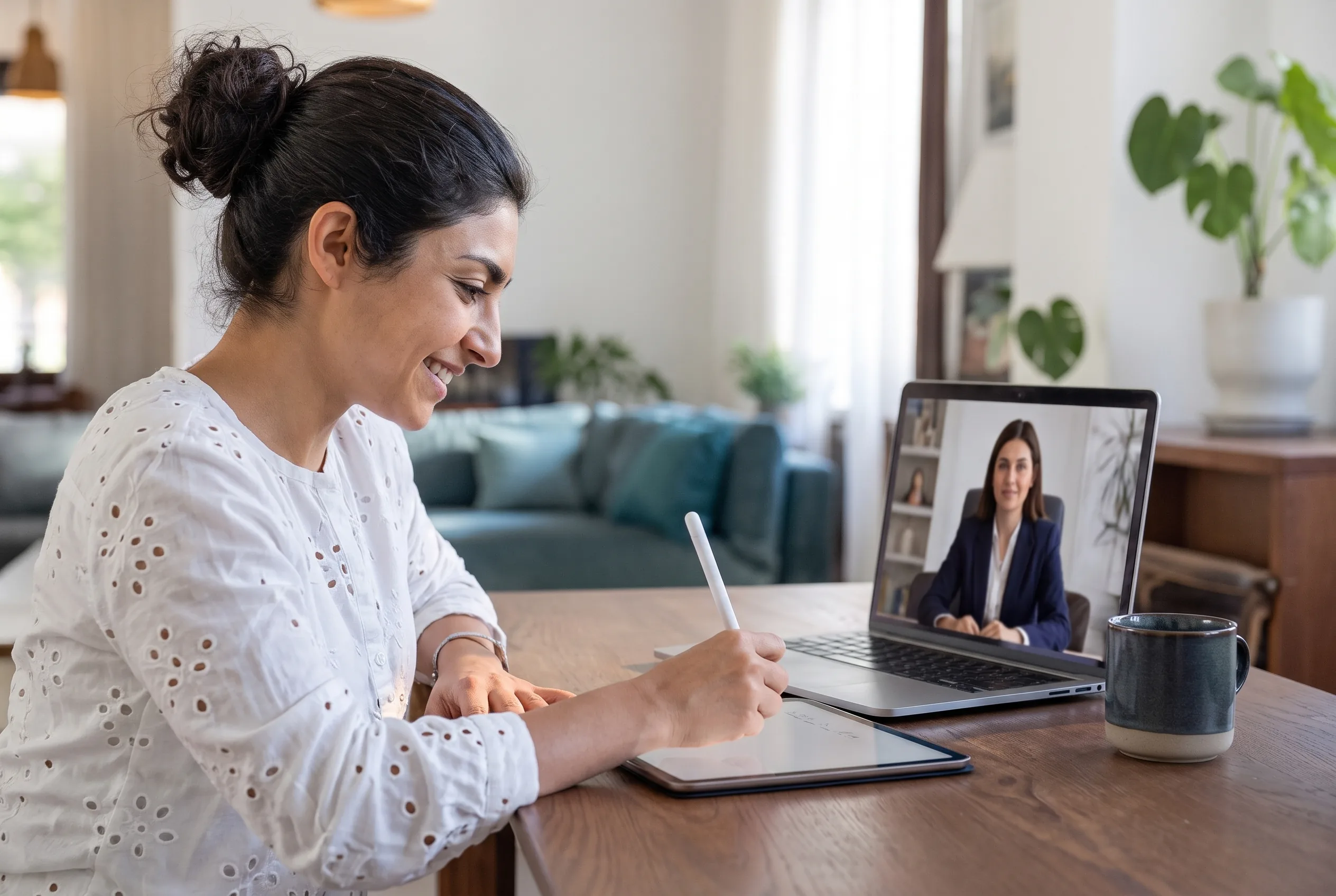 A woman signs on a tablet during a video call with a notary